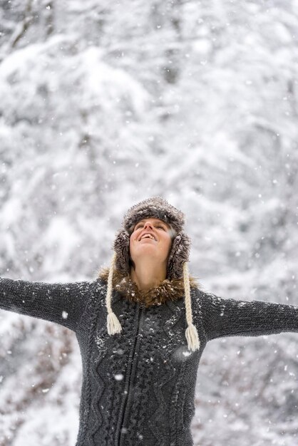 Foto jonge vrouw viert de winter met haar armen wijd uitgestrekt