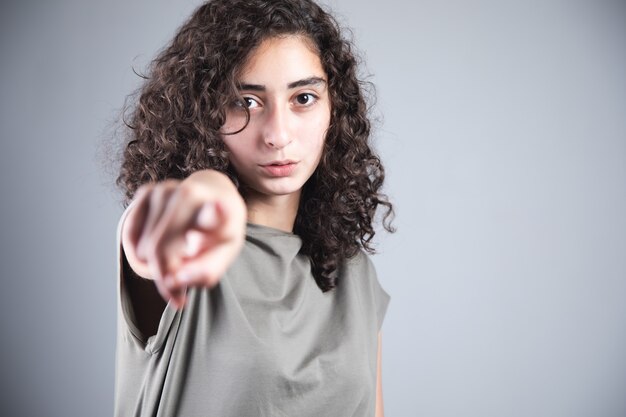 Jonge vrouw vinger teken je op grijze achtergrond