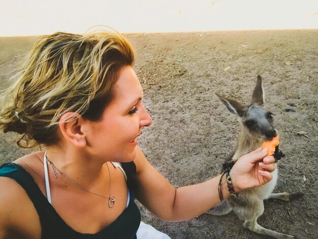 Foto jonge vrouw voedt kangoeroe op het veld