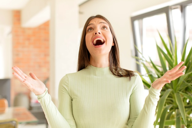 Jonge vrouw voelt zich gelukkig verbaasd gelukkig en verrast de overwinning te vieren met beide handen in de lucht