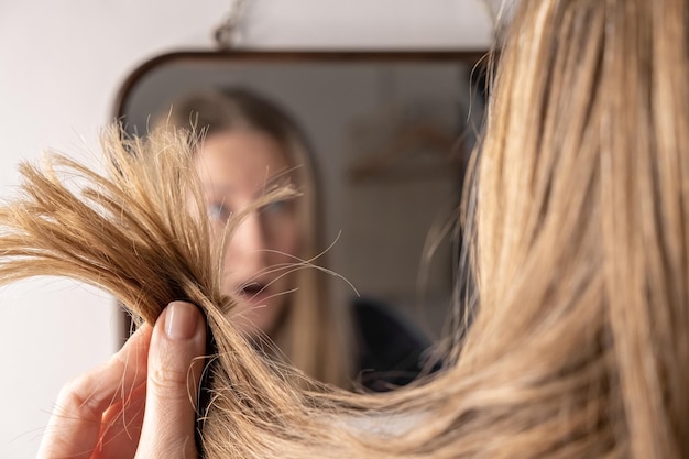 Foto jonge vrouw voor de spiegel verdrietig over haar haarverlies schade probleem