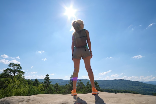 Jonge vrouw wandelaar staan alleen op berg voetpad genieten van uitzicht op de zomer natuur op wildernis parcours op warme zomerdag actieve manier van leven concept