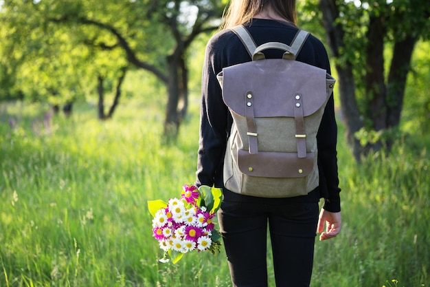 Jonge vrouw wandelen met rugzak en bloemen in de hand