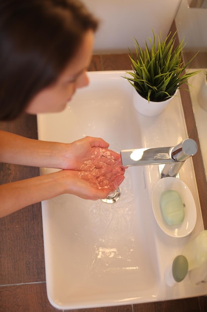 Jonge vrouw wast haar gezicht met schoon water in de badkamer