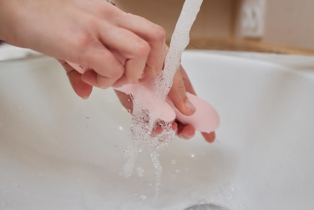 Jonge vrouw wast thuis een seksspeeltje in de gootsteen