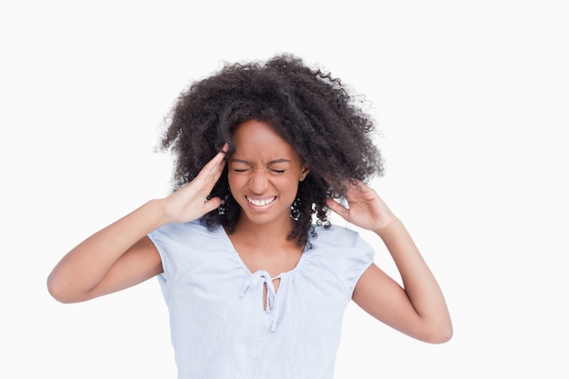 Jonge vrouw wat betreft haar tempels terwijl het zijn boos