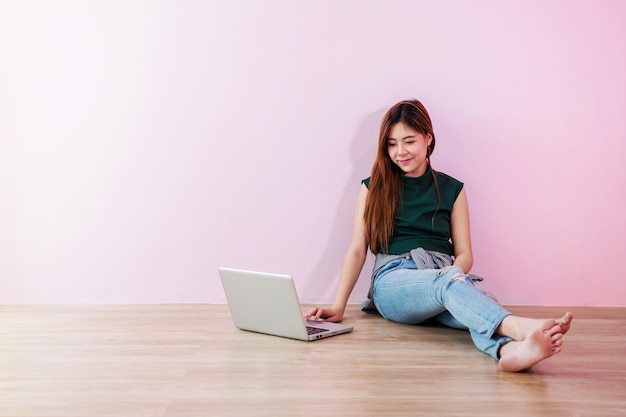 Jonge vrouw werken of studeren op Laptop, zitten op de vloer en glimlachen