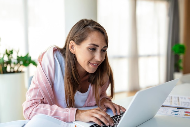 Jonge vrouw werkende laptop Zakenvrouw druk bezig met laptopcomputer op kantoor Zakenvrouw zittend op een heldere moderne werkplek en typen op laptop