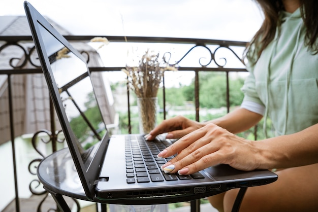 Jonge vrouw werkt op een laptop op het externe werkconcept op het terras