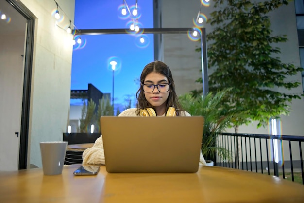 Jonge vrouw werkt 's avonds heel laat op haar laptop in een café