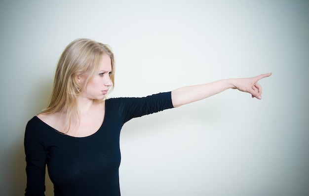 Foto jonge vrouw wijst weg tegen een witte achtergrond