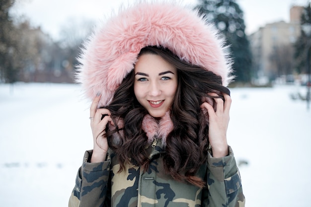 Jonge vrouw winter portret. Ondiepe DOF. Mooi lachend gezicht van mannequin met rode lippen en bontcapuchon