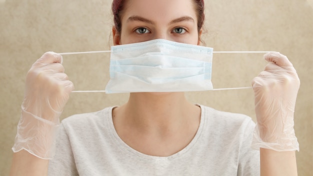 Jonge vrouw zet een medisch masker op, preventie van coronavirus, uitbraak van COVID-19