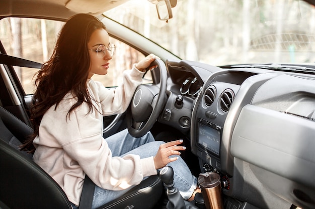 Jonge vrouw zit in een auto. Mooie brunette . Landreis met de auto