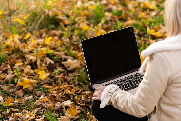 Jonge vrouw zit in park met laptop