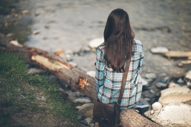 Jonge vrouw zit langs de rivier