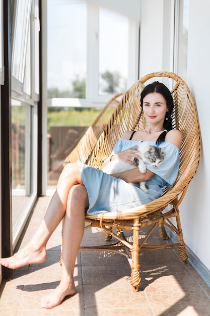 Foto jonge vrouw zit met kat op houten stoel op terras