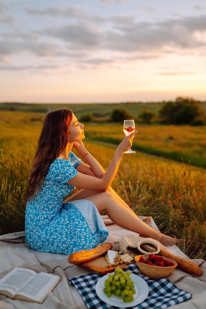 Jonge vrouw zit op een plaid met een boek Zomerpicknick in de natuur Gezonde voeding