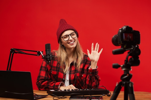 Jonge vrouw zittend aan de tafel die ze werkte als een radio-dj, ze lachte en zwaaide naar de camera in de studio