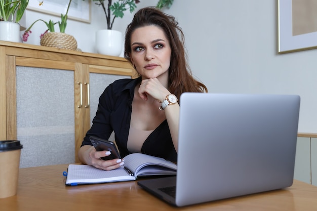 Jonge vrouw zittend aan een bureau en thuis werken