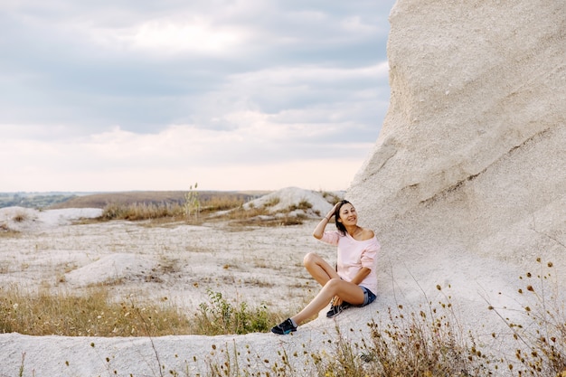 Jonge vrouw zittend op de grond op een klif, genieten van vakantie.