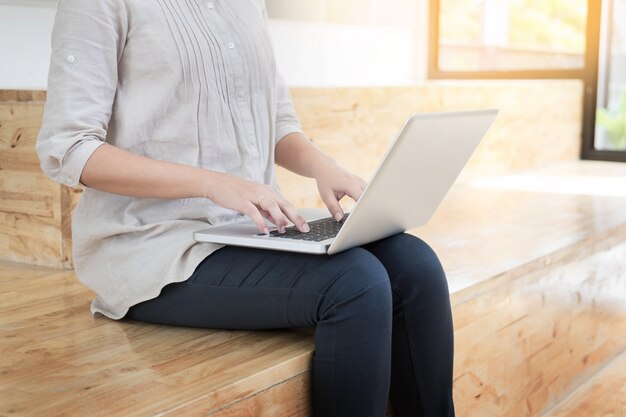 Jonge vrouw zittend op de vloer met laptop in de bibliotheek, onderwijs en technologie concept.