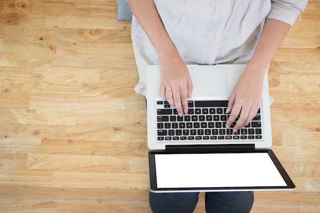 Jonge vrouw zittend op de vloer met laptop in de bibliotheek, onderwijs en technologie concept.