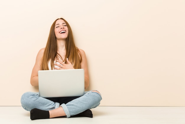 Jonge vrouw zittend op de vloer met laptop