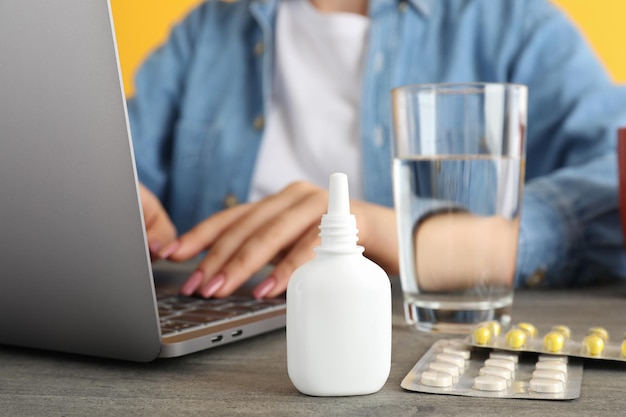 Jonge vrouw zittend op de werkplek met medicijnen, seizoensgebonden koudebehandeling