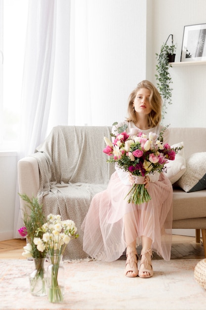 Jonge vrouw zittend op een bank met boeket bloemen