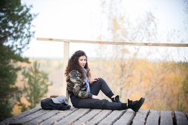 Jonge vrouw zittend op een platform op een achtergrond van het bos daglicht