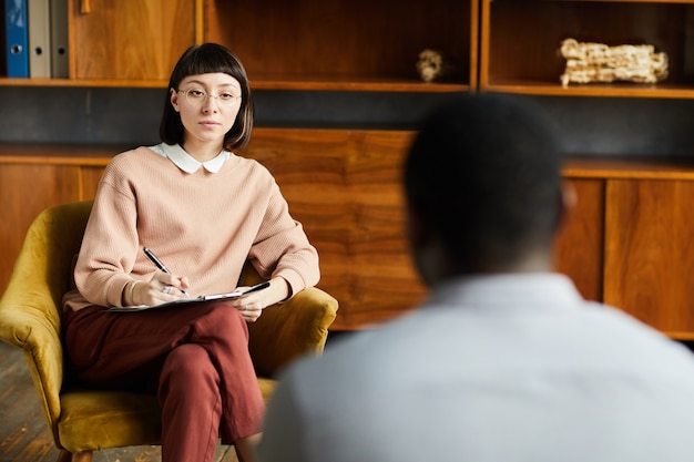 Foto jonge vrouw zittend op een stoel tijdens haar psychologietherapie en in gesprek met de psycholoog