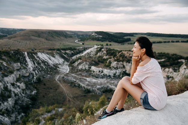 Jonge vrouw zittend op een top van een berg genieten van landschappen.