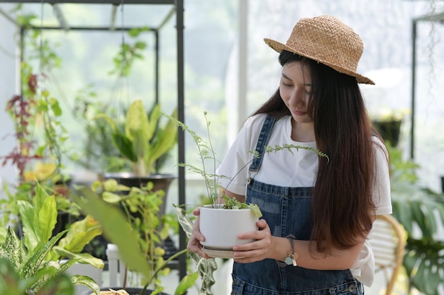 Jonge vrouw zorgt voor bomen planten en verzorgen van apparatuur planten in kassen kleine bedrijven