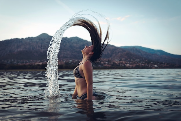 Jonge vrouw zwemmen in meer bij zonsondergang levensstijl concept