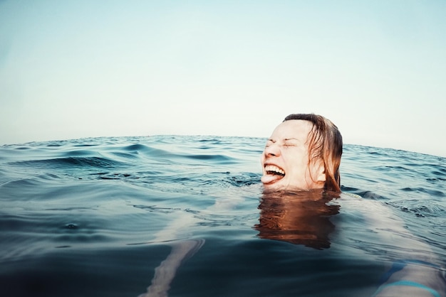 Jonge vrouw zwemt in de zee tegen de lucht.