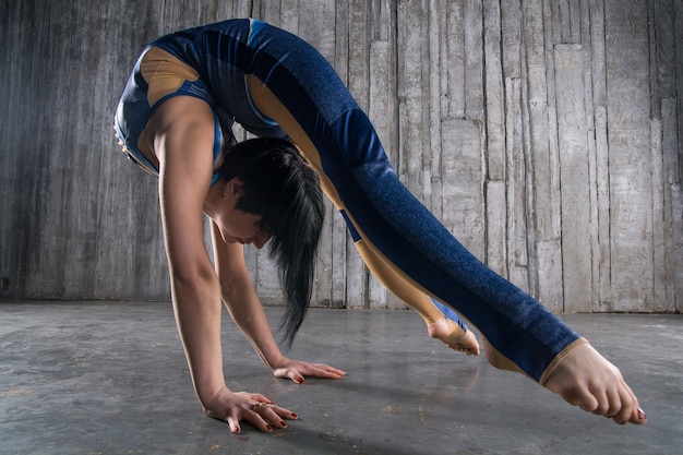 Foto jonge vrouwelijke acrobat standing on overhandigen grijze oppervlakte in fotostudio