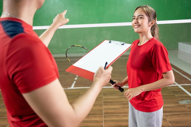 Jonge vrouwelijke badmintonspeler luisteren naar instructies van coach