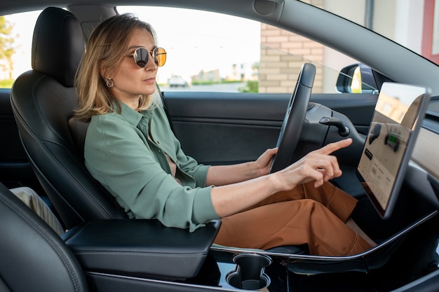 Jonge vrouwelijke chauffeur die naar het display wijst terwijl ze de plaats van bestemming kiest