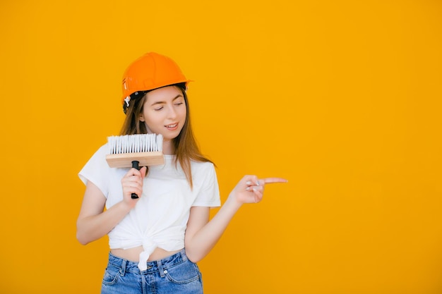 Jonge vrouwelijke decorateur met verfroller op gele achtergrond