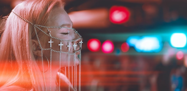 Jonge vrouwelijke dj in een nachtclub op de console het meisje draagt een wit pak en sieraden op haar gezicht