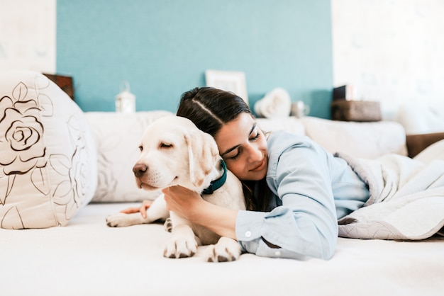 Jonge vrouwelijke eigenaar die in bed met het puppy van labrador slapen.