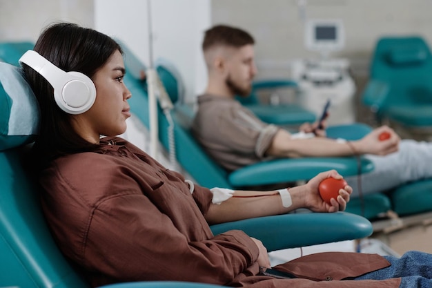 Jonge vrouwelijke en mannelijke bloeddonoren ontspannen zich in fauteuils in de kliniek