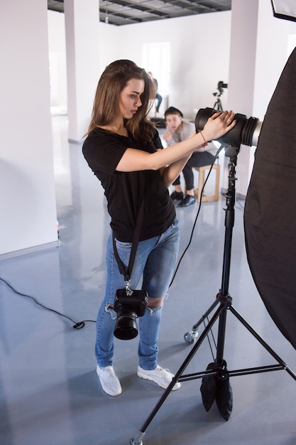 Jonge vrouwelijke fotograaf werkt in studio