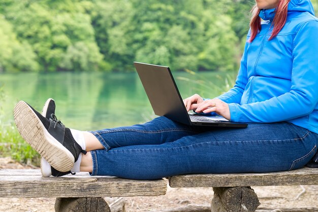 Jonge vrouwelijke freelancer die met laptop werkt met prachtig uitzicht op bos en meer