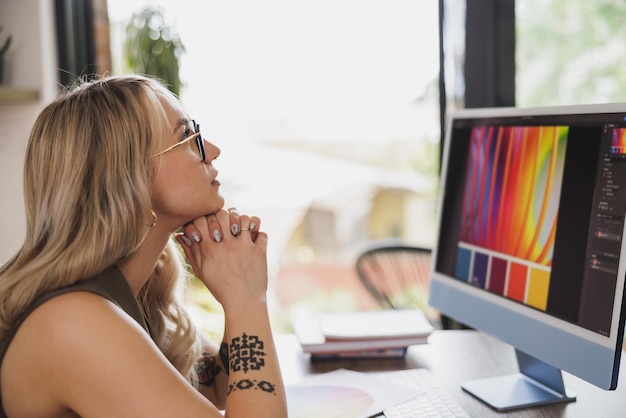 Jonge vrouwelijke freelancer-ontwerper die er attent uitziet terwijl ze werkt vanuit haar thuiskantoor.