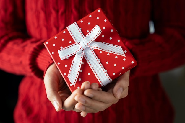 Jonge vrouwelijke handen met geschenkdoos met lint