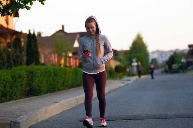 Jonge vrouwelijke hardloper, atleet tijdens het joggen in de straat van de stad in de zon.