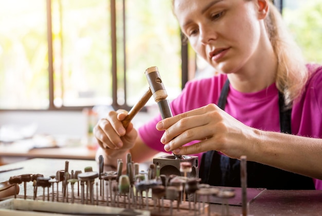 Jonge vrouwelijke juwelier die sieraden maakt in een werkplaats