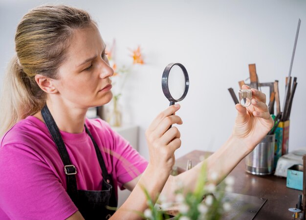 Jonge vrouwelijke juwelier sieraden maken in werkplaats